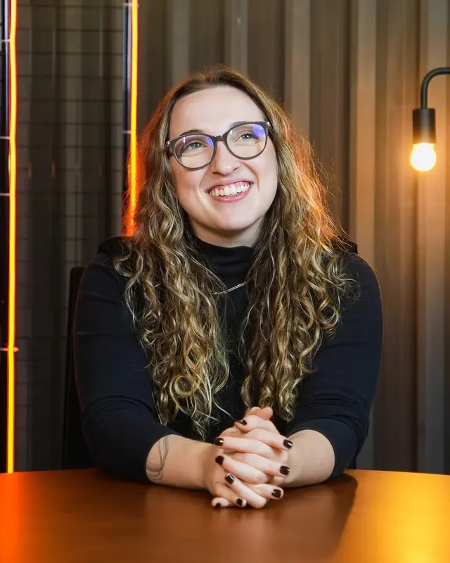 Gio Mangoni sentada à mesa, sorrindo